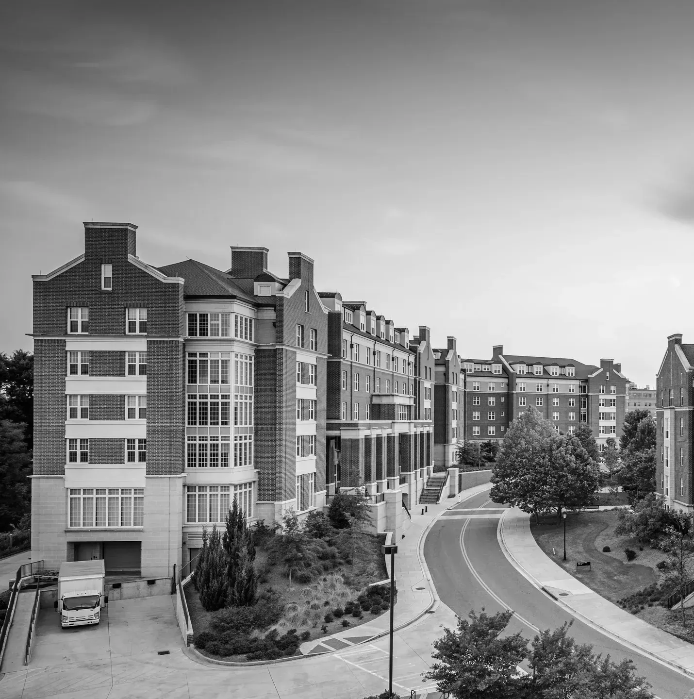 Aerial view of modern brick residential apartment complex with curved driveway and surrounding landscaping.