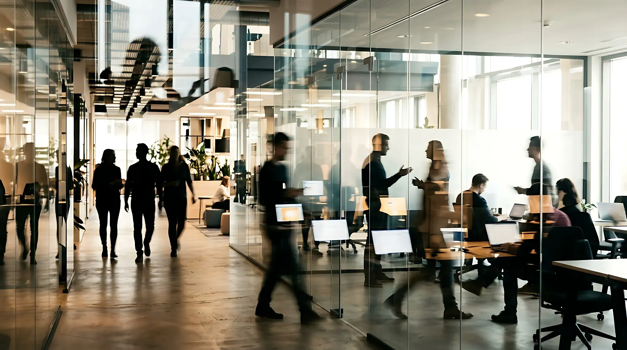 Modern office building interior with glass partitions, multiple employees working and walking through collaborative workspace