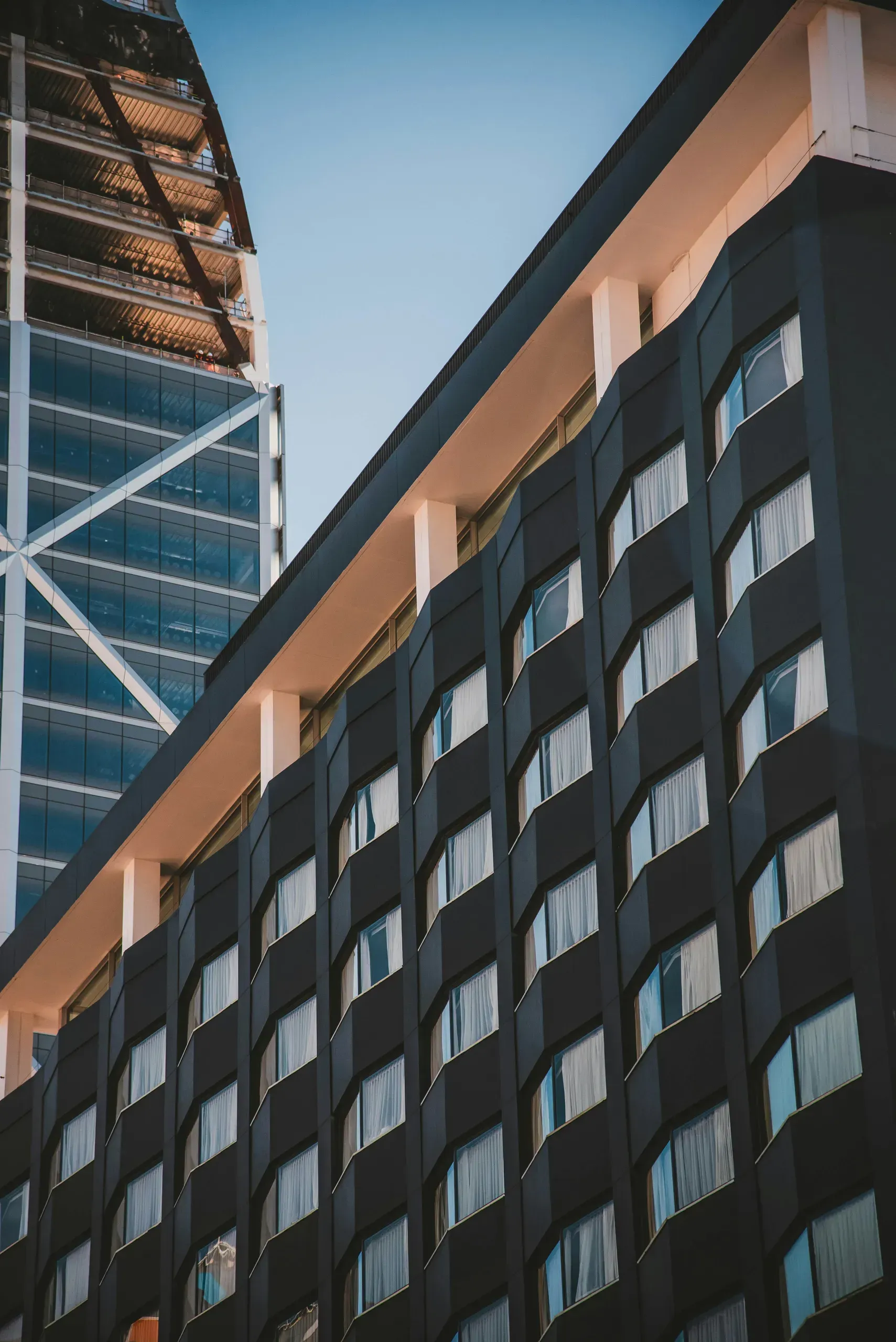Modern residential apartment building with uniform windows and bronze-colored roof overhang against clear sky