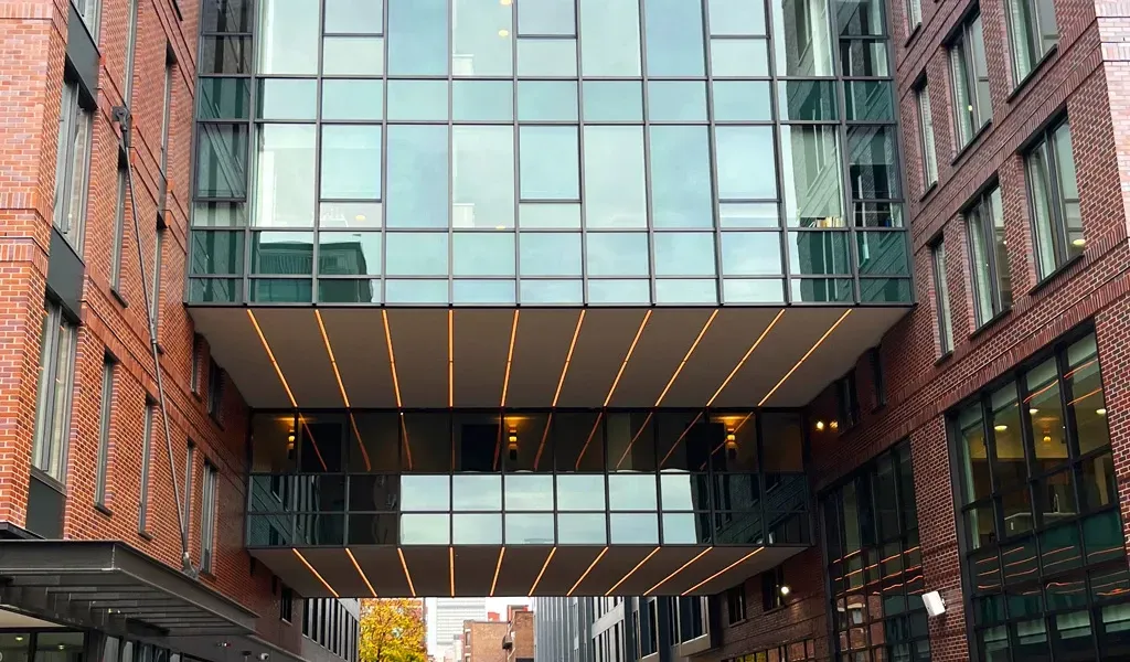 Modern glass and steel atrium connecting historic red brick buildings in urban courtyard
